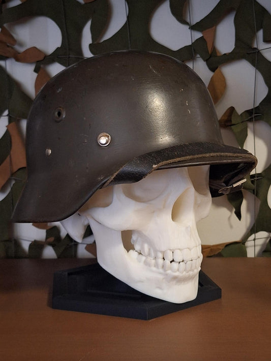 Skull with a helmet on a stand against a camouflage-patterned background